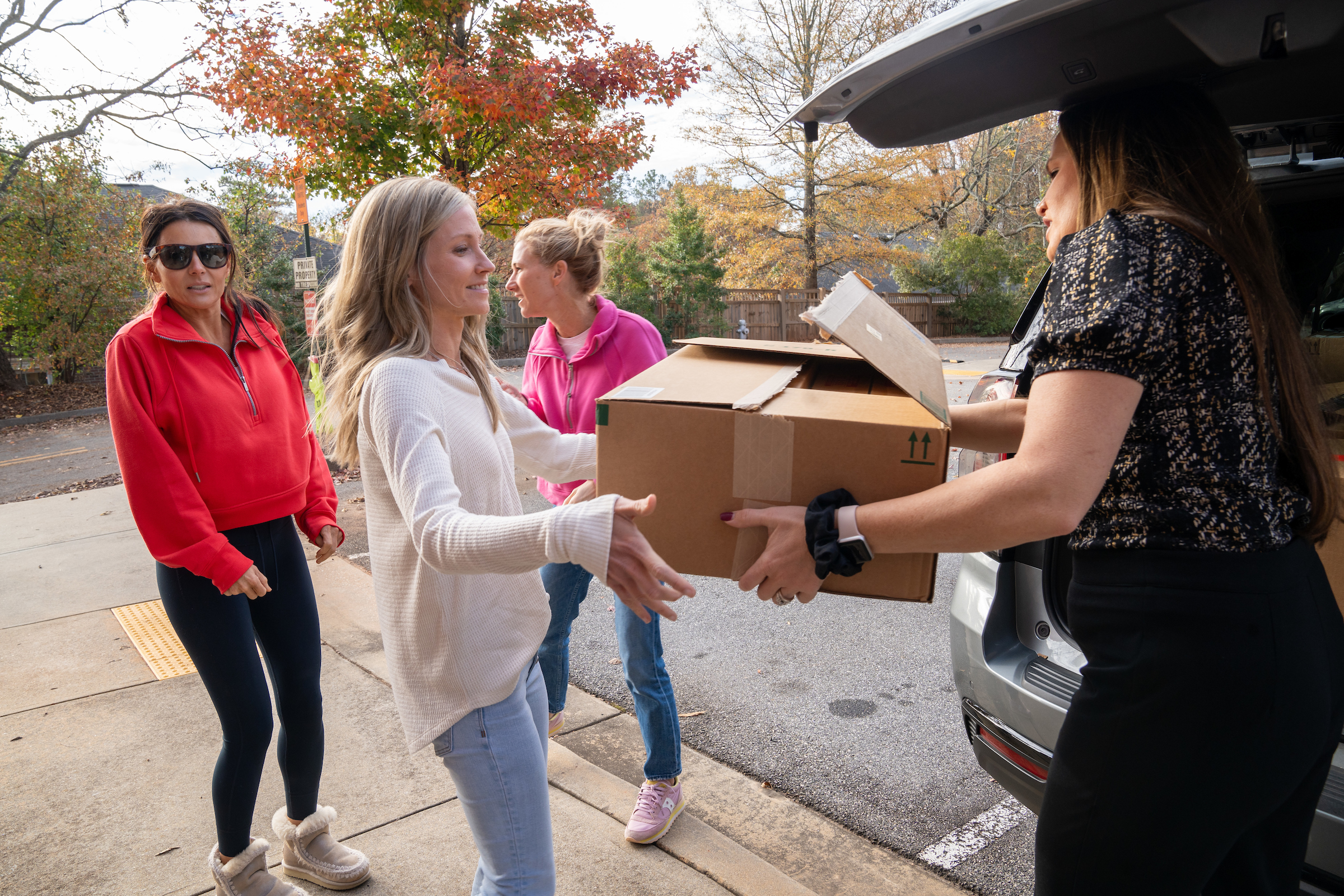 A woman hands a box of donations to another woman