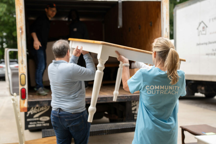 A man and woman load a table into a moving truck