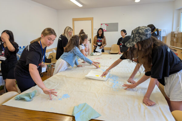Students create artwork on a large canvas at a camp for Polish and Ukrainian youth (GO Poland)