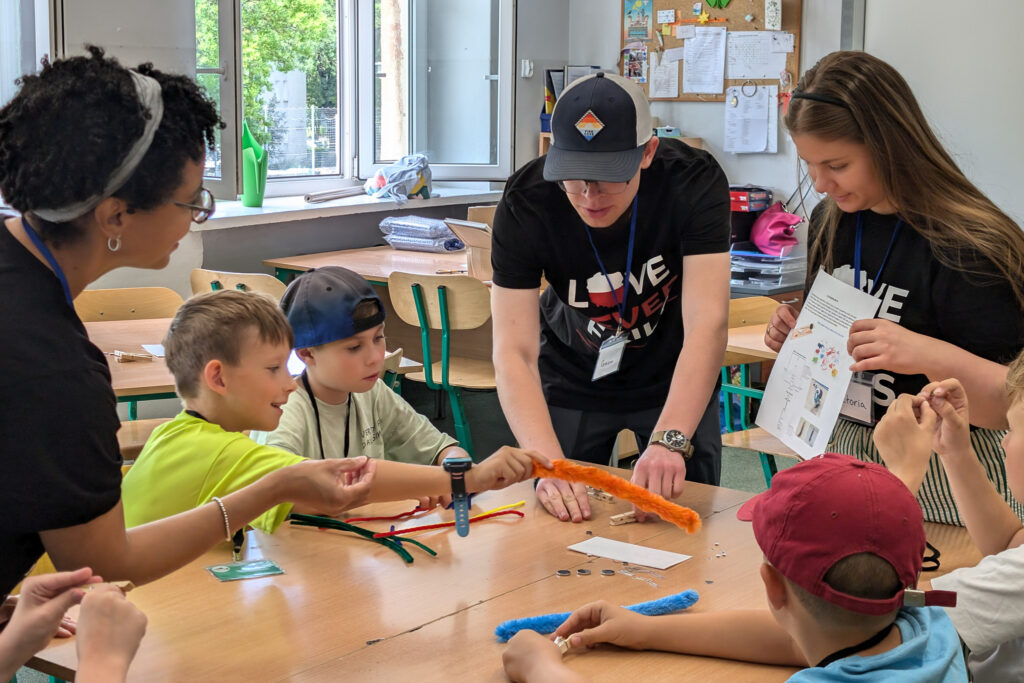 A volunteer helps a child with a craft at a camp for Polish and Ukrainian youth (GO Poland)