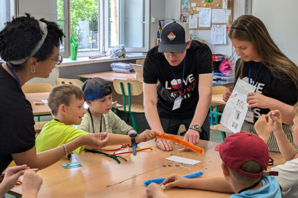 A volunteer helps a child with a craft at a camp for Polish and Ukrainian youth (GO Poland)