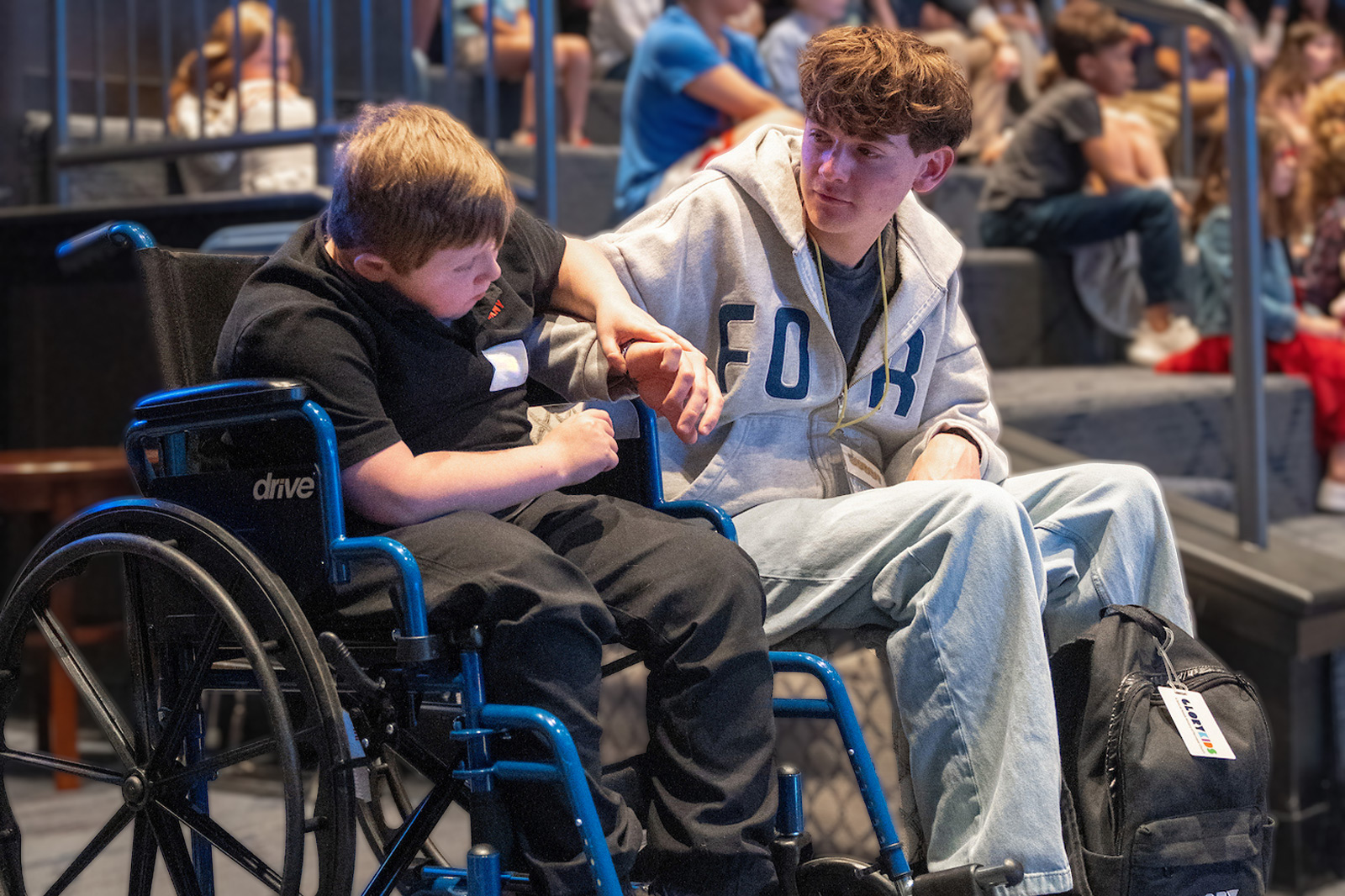 A volunteeer holds hands with a student in a wheelchair