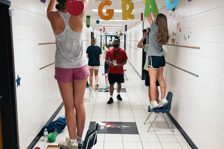 Teens hang welcome signs to decorate a public school hallway