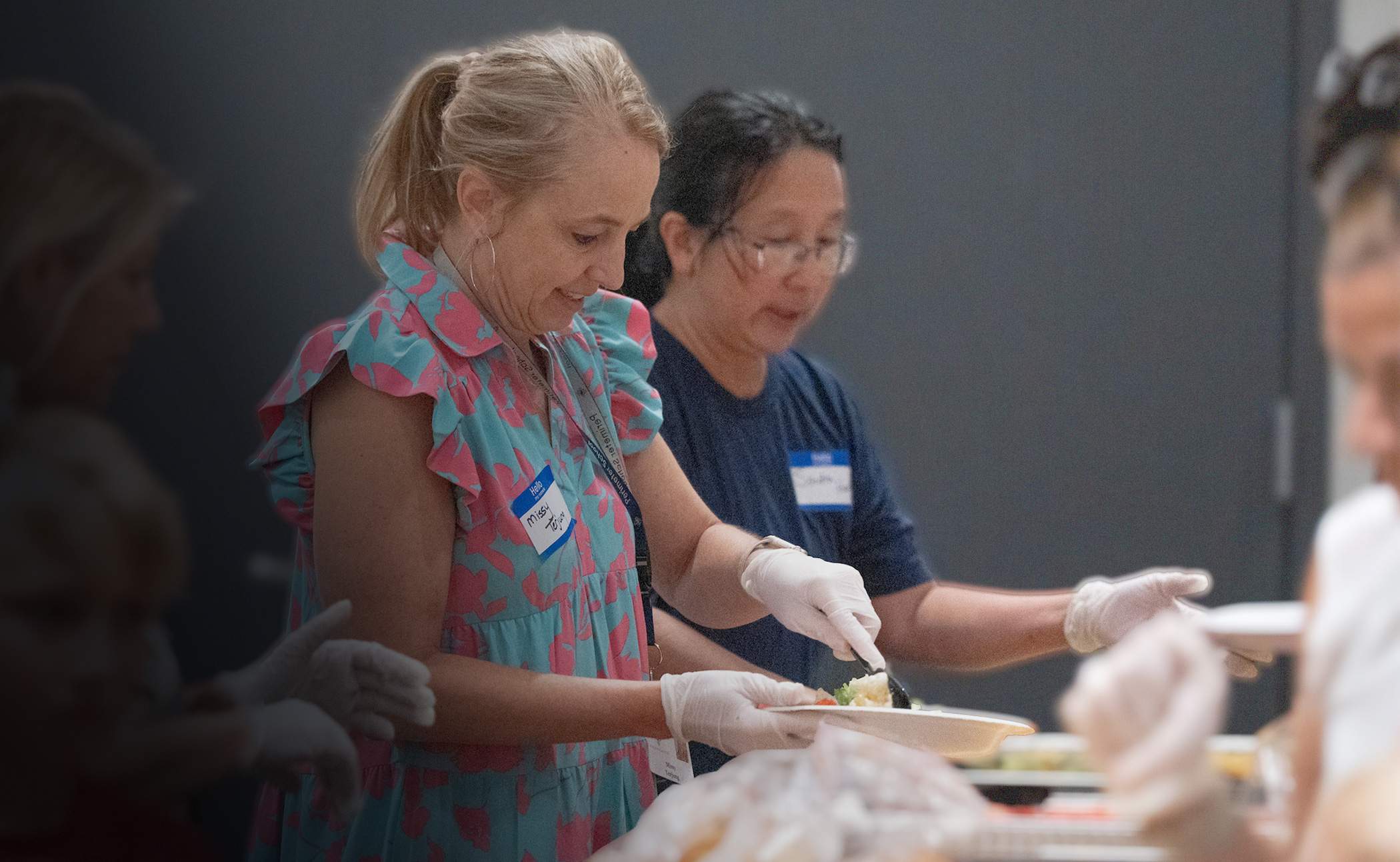 Adult volunteers serve food at the Rush summer conference