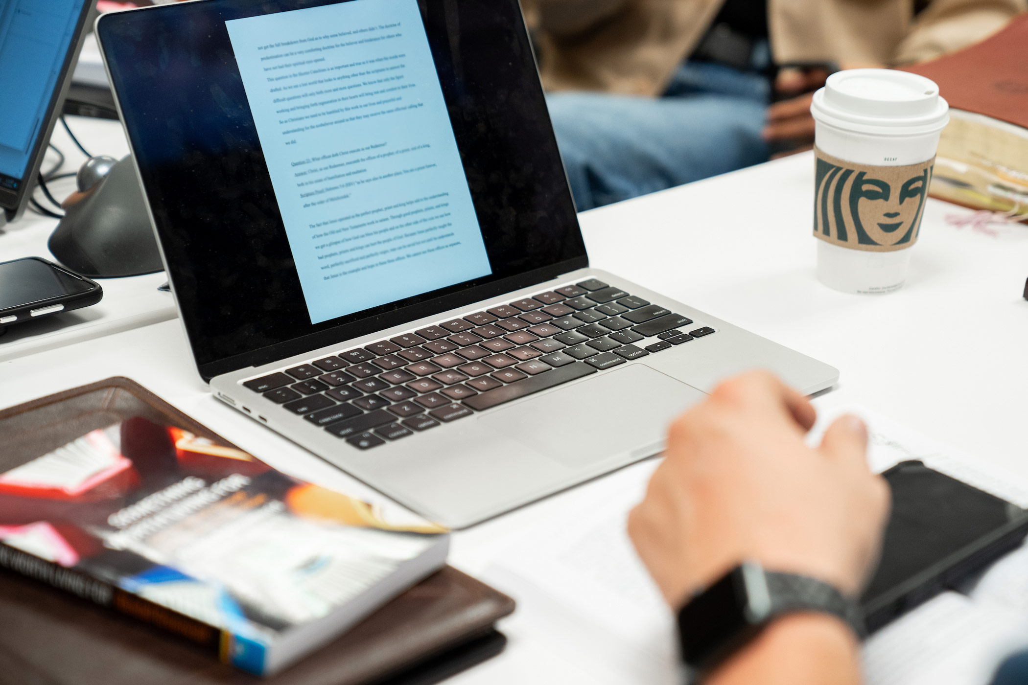 A close up view of a seminary student's workspace with books and an open laptop screen