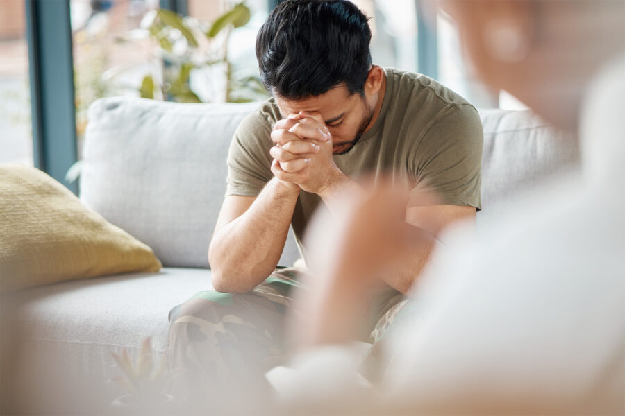 A man clasps his hands in front of his face in thoughtful reflection