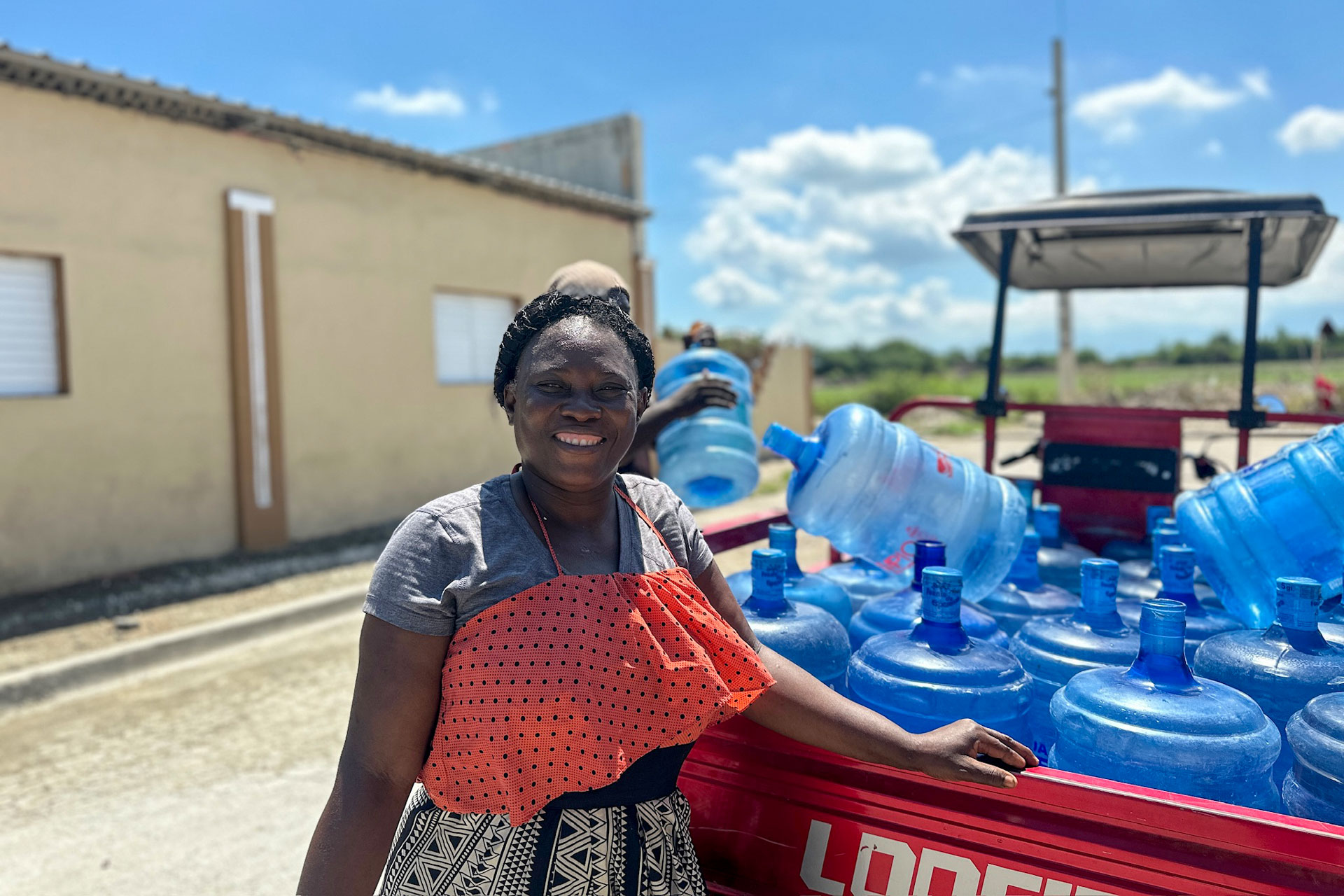 A woman smiles in front of a truckload of clean water in the Dominican Republic